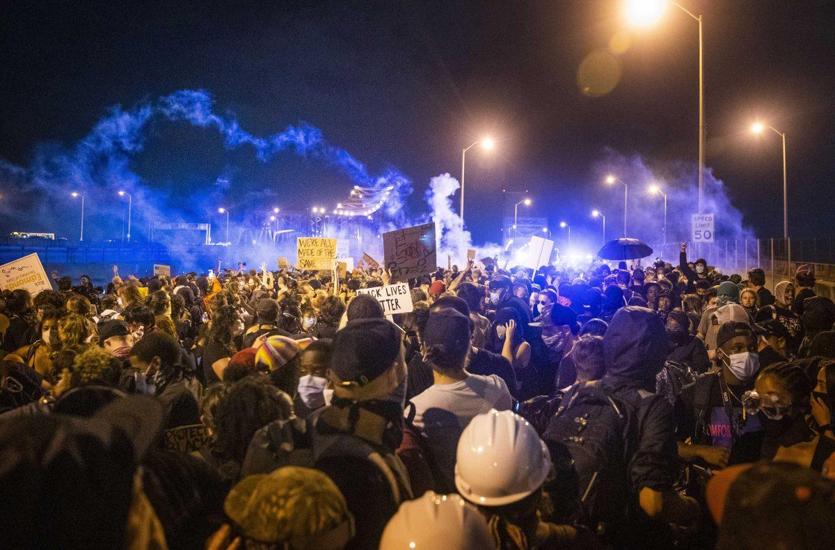 Police officers spray teargas at protesters by the Crescent City Connection bridge in New Orleans, Wednesday, June 3, 2020, during a protest over the death of George Floyd, who died May 25 after being restrained by police in Minneapolis. (Sophia Germer/The Advocate via AP)