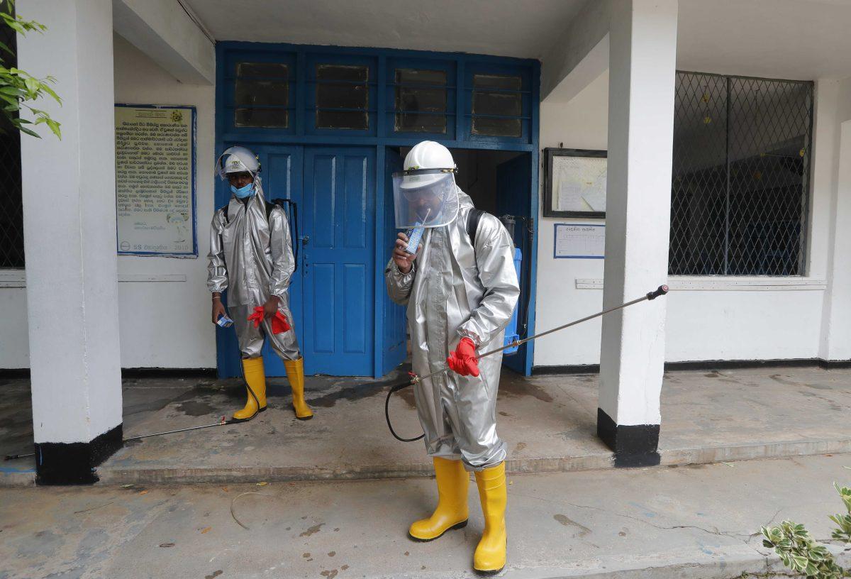 A member of Sri Lanka's St John's ambulance service drinks a beverage during a break in between a spraying of disinfectants at a public school to prevent the spread of coronavirus in Colombo, Sri Lanka, Monday, June 22, 2020. (AP Photo/Eranga Jayawardena)