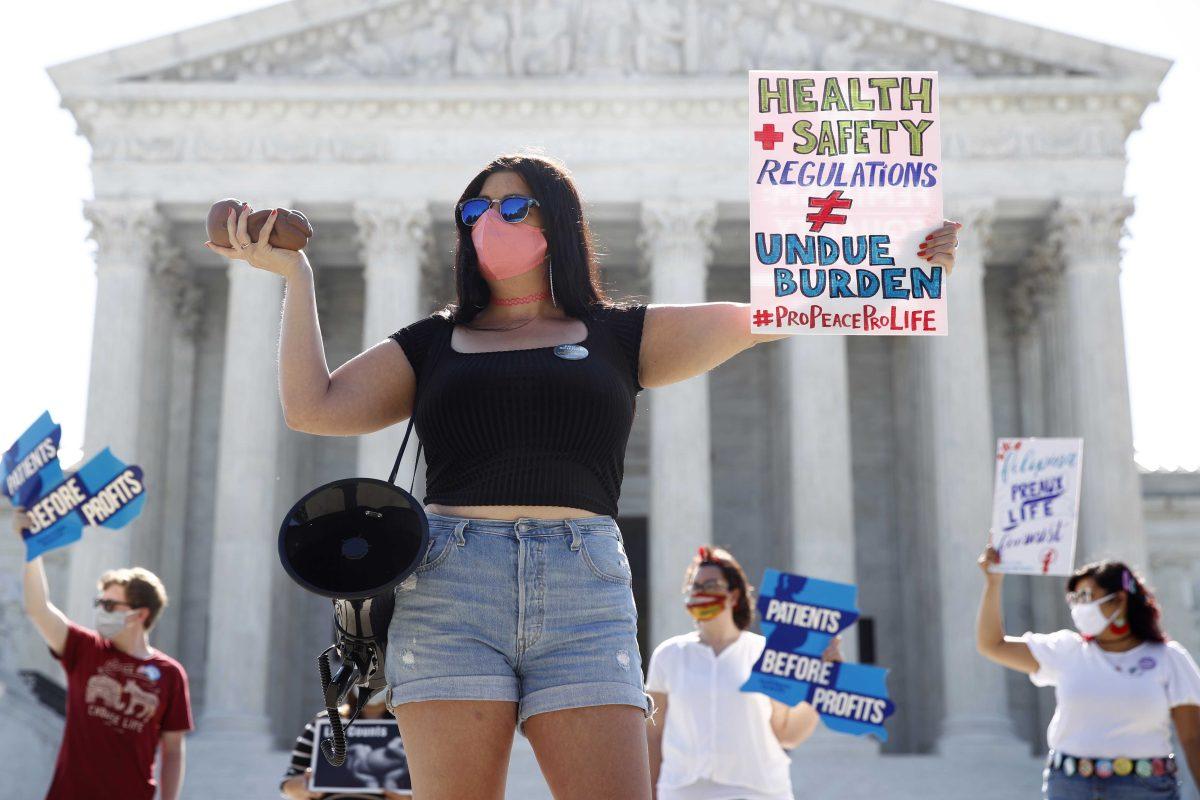 Terrisa Bukovinac, founder of Pro-Life San Francisco, holds a model of a fetus as she and other anti-abortion protesters wait outside the Supreme Court for a decision, Monday, June 29, 2020. The Supreme Court has struck down a Louisiana law regulating abortion clinics, reasserting a commitment to abortion rights over fierce opposition from dissenting conservative justices in the first big abortion case of the Trump era. (AP Photo/Patrick Semansky)