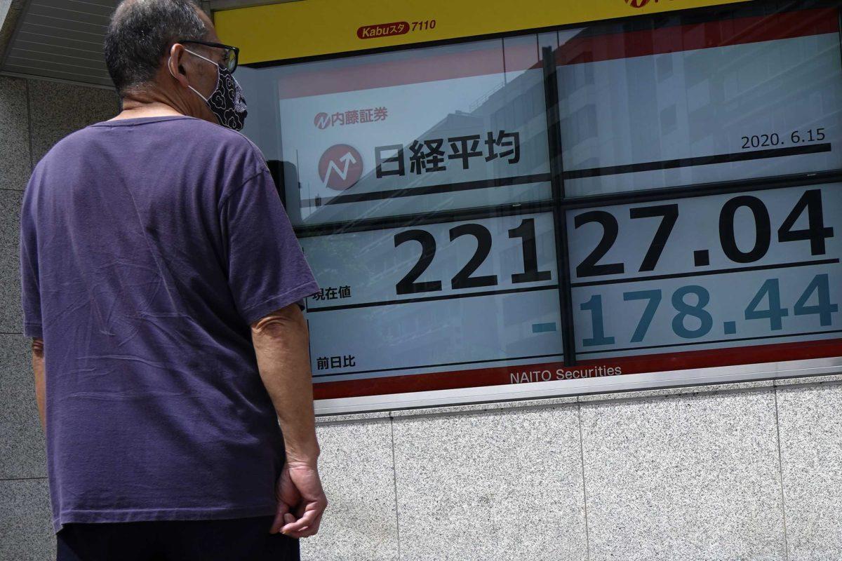 A man looks at an electronic stock board showing Japan's Nikkei 225 index at a securities firm in Tokyo Monday, June 15, 2020. Asian shares were mostly lower Monday on concern over a resurgence of coronavirus cases and pessimism after Wall Street posted its worst week in nearly three months. (AP Photo/Eugene Hoshiko)