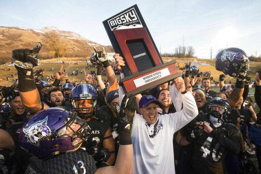 In this Nov. 18, 2017, file photo, Weber State coach Jay Hill hoists the trophy after they defeated Idaho State in an NCAA college football game for a share of the Big Sky Conference title in Ogden, Utah. The The Big Sky Conference postponed its football season on Friday, Aug. 7, 2020, to the spring because of the coronavirus pandemic and called for the FCS playoffs to be moved to the second semester as well.&#160;