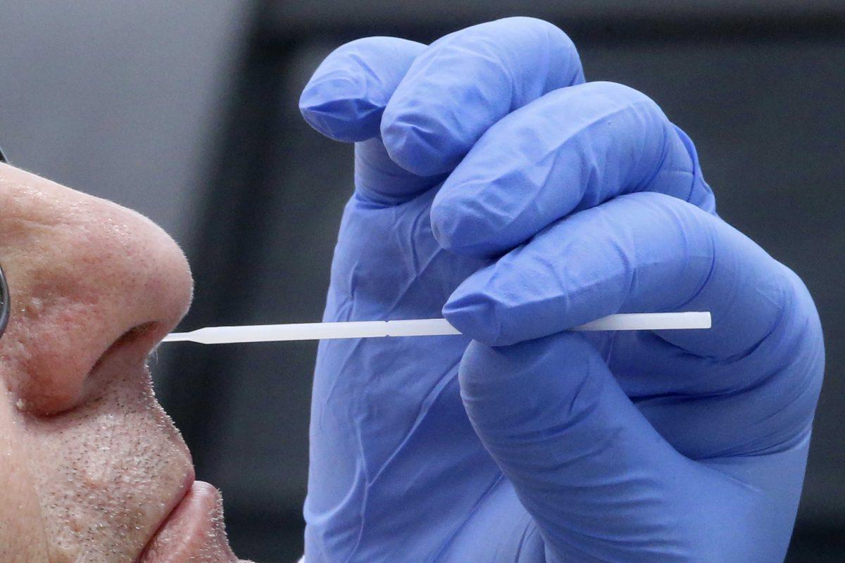 FILE - In this June 12, 2020 file photo Salt Lake County Health Department's public health nurse Lee Cherie Booth performs a coronavirus test outside the Salt Lake County Health Department in Salt Lake City. Having access to quick coronavirus test results will play an important role in resuming sporting events, keeping factories and businesses open, and returning to school in the fall. But an Associated Press survey of selected states found it&#8217;s still taking days in some cases for results to come back despite an increase in the availability of testing across the U.S. Public health experts say testing delays present a major hurdle to reducing infections. (AP Photo/Rick Bowmer, File)