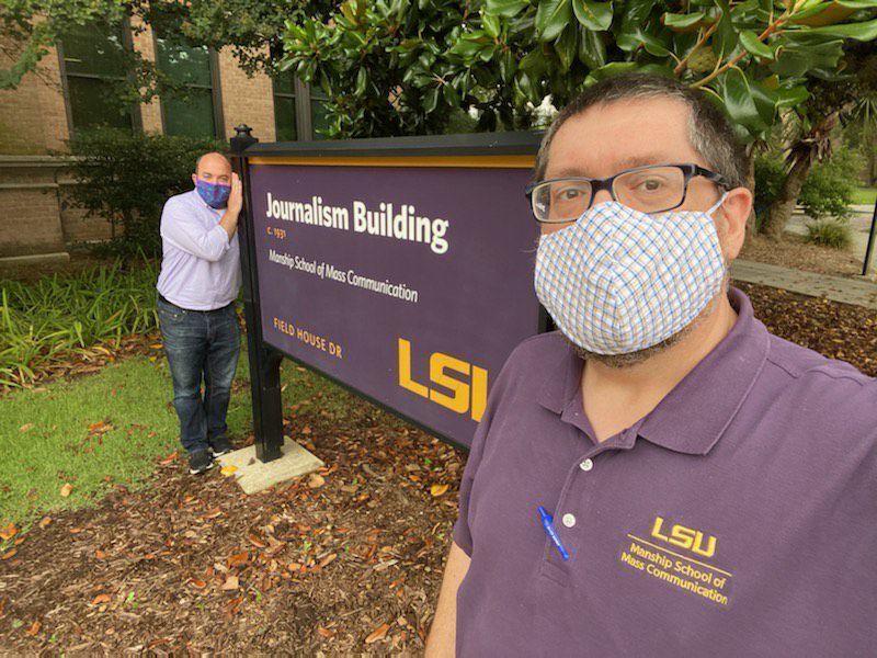 Manship School Dean Martin Johnson (right) and Associate Dean Josh Grimm (left) mask up in front of the Journalism Building.&#160;