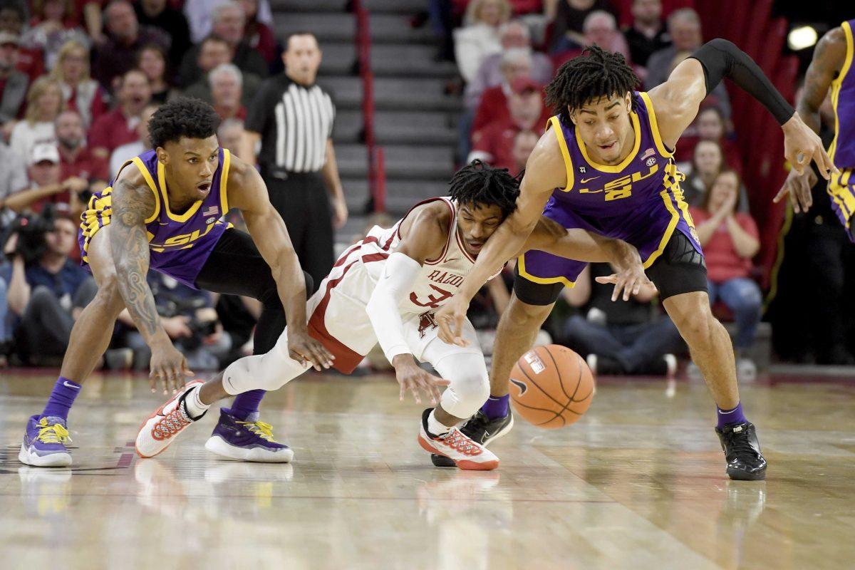 LSU defenders Marlon Taylor (14) and Trendon Watford (2) try to steal the ball from Arkansas forward Jimmy Whitt Jr.&#160;(33) during the second half of an NCAA college basketball game Wednesday, March 4, 2020, in Fayetteville, Ark. (AP Photo/Michael Woods)