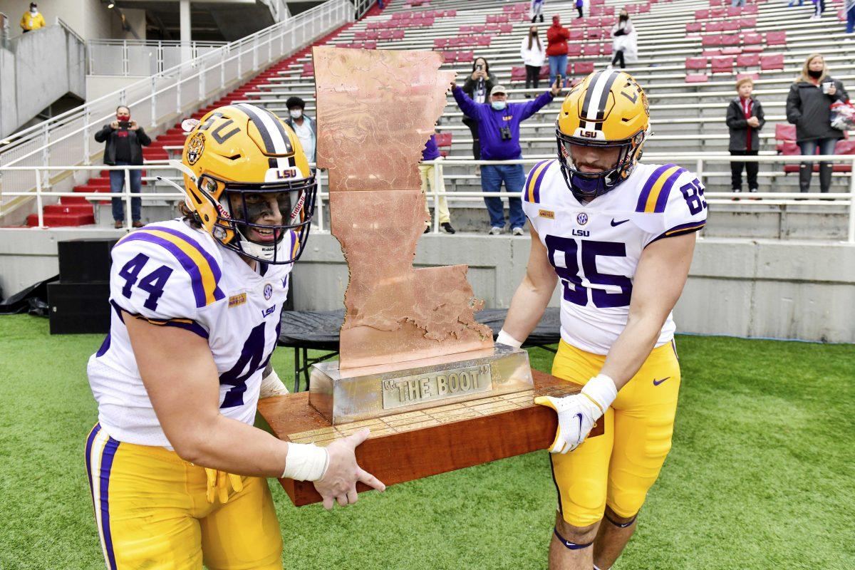 LSU players Tory Carter (44) and Nick Storz (85) carry "The Boot" trophy off the field after defeating Arkansas 27-24 in an NCAA college football game Saturday, Nov. 21, 2020, in Fayetteville, Ark. (AP Photo/Michael Woods)