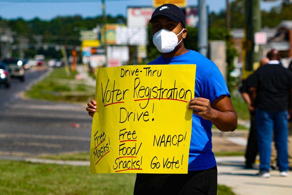 Computer engineering junior Nicholas James displays sign encouraging people to register to vote on Saturday, Oct. 3, 2020 during a voter registration drive on Gardere Lane in Baton Rouge, LA.