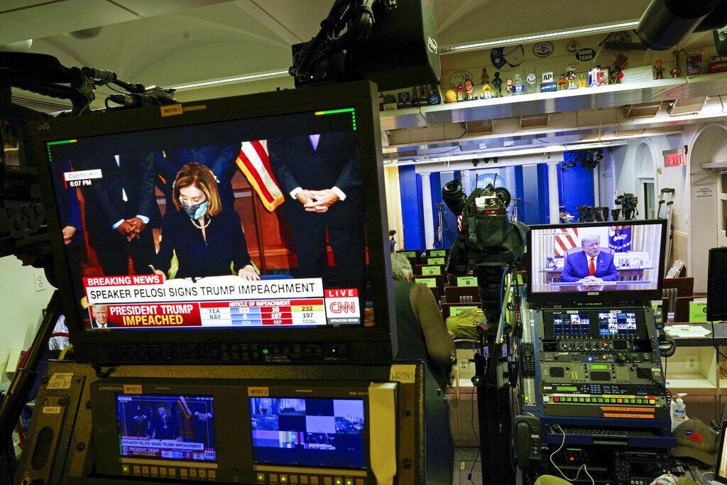 President Donald Trump is seen speaking on a television monitor in an empty press briefing room at the White House in Washington, from a video statement released by President Donald Trump on Twitter as it is broadcast by FOX News, after the U.S. House impeached him, Wednesday, Jan. 13, 2021. At left is a replay of House Speaker Nancy Pelosi signing the article of impeachment, as broadcast by CNN.&#160;