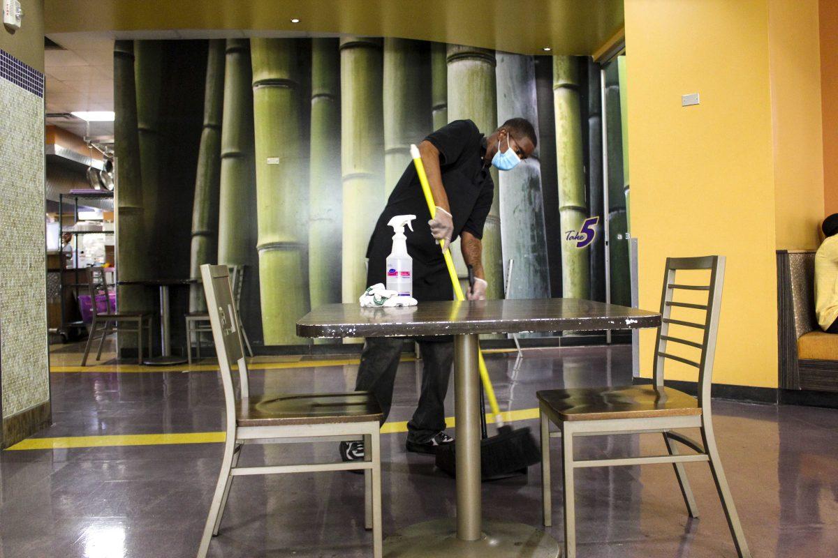 A custodial worker cleans a table Friday, Nov. 13, 2020 after each use at The 5 dining hall.