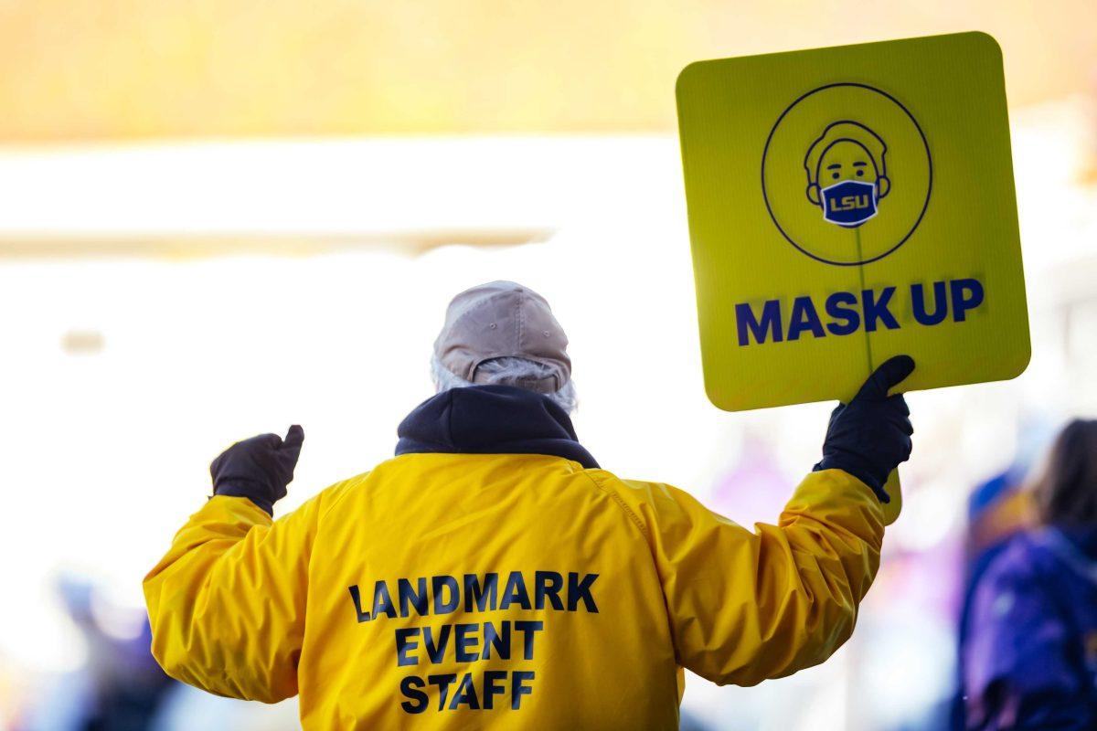 A Landmark security guard holds up a "mask up" sign to fans Saturday, Feb. 20, 2021 during LSU's 6-1 win over Air Force at Alex Box Stadium on Gourrier Avenue in Baton Rouge, La.