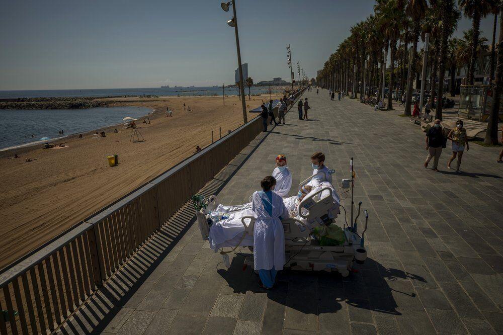 FILE - In this Sept. 4, 2020, file photo, Francisco Espana, 60, is surrounded by members of his medical team as he looks at the Mediterranean sea from a promenade next to the "Hospital del Mar" in Barcelona, Spain. Francisco spent 52 days in the Intensive Care unit at the hospital due to coronavirus, but today he was allowed by his doctors to spend almost ten minutes at the seaside as part of his recovery therapy. (AP Photo/Emilio Morenatti, File)