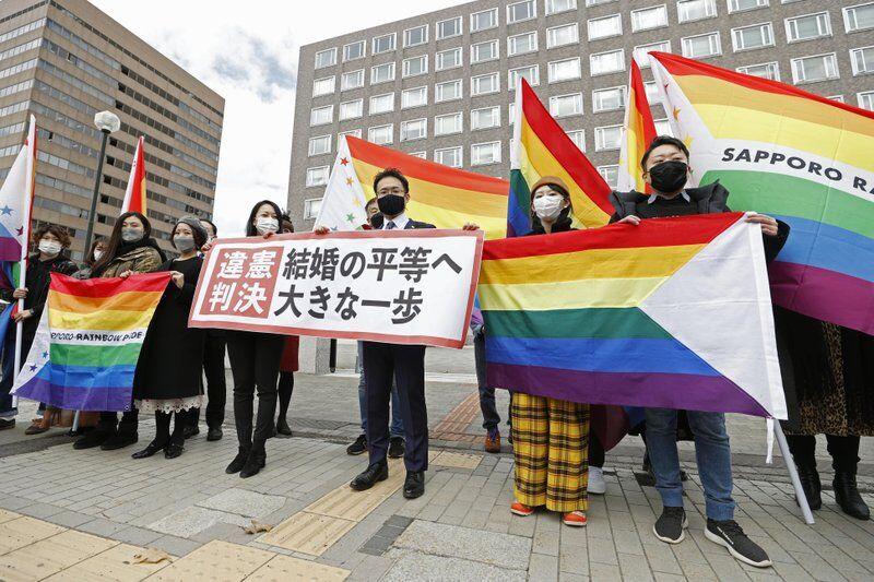 Plaintiffs' lawyers and supporters hold rainbow flags and a banner that reads: "Unconstitutional judgment" outside Sapporo District Court after a court rule, in Sapporo, northern Japan, Wednesday, March 17, 2021. The court ruled the government's ban on same-sex marriages is unconstitutional, recognizing the rights of same-sex couples for the first time in the only Group of Seven country that doesn't acknowledge their legal partnership. (Yohei Fukai/Kyodo News via AP)