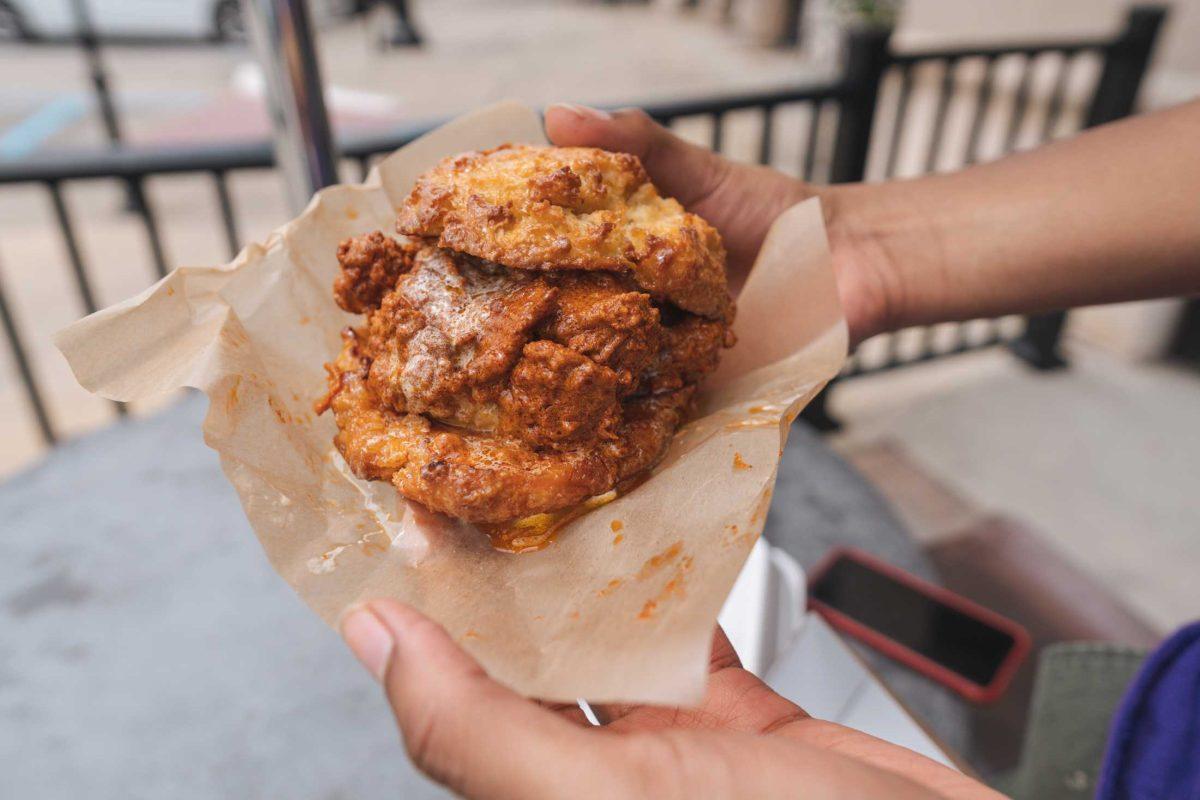 A Hot Chicken and Honey Butter French Toast Biscuit sticks out of its wrapper on April 15, 2021 on the patio of District Donuts in Baton Rouge.