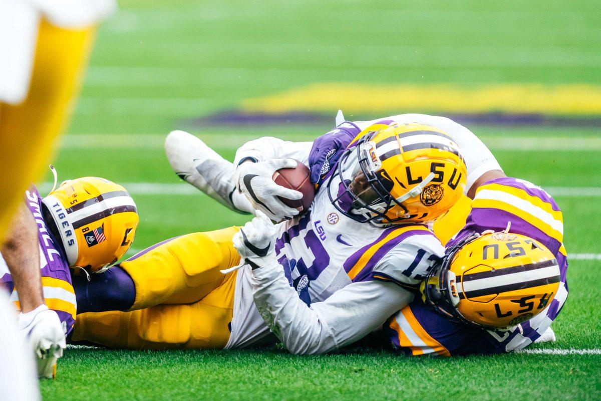 LSU football senior linebacker Damone Clark (18) tackles senior wide receiver Jontre Kirklin (13) Saturday, April 17, 2021 where the LSU football white team defeated purple 23-14 during their spring game at Tiger Stadium in Baton Rouge, La.