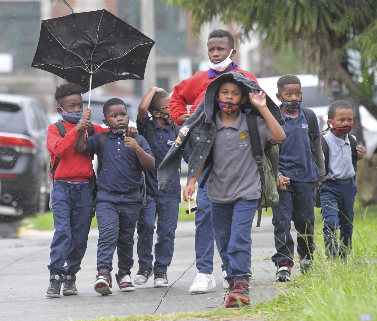 Children try to protect themselves from the rain at the end of the school day at the Dryades YMCA along Oretha Castle Haley Blvd., Friday, Aug. 27, 2021, in New Orleans, as residents prepare for Hurricane Ida. (Max Becherer/The Times-Picayune/The New Orleans Advocate via AP)