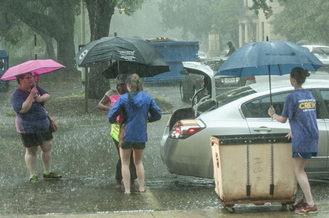 Students and parents fight the rain to haul luggage into the dorms on Wednesday, Aug. 19, 2015, at Evangeline Hall.