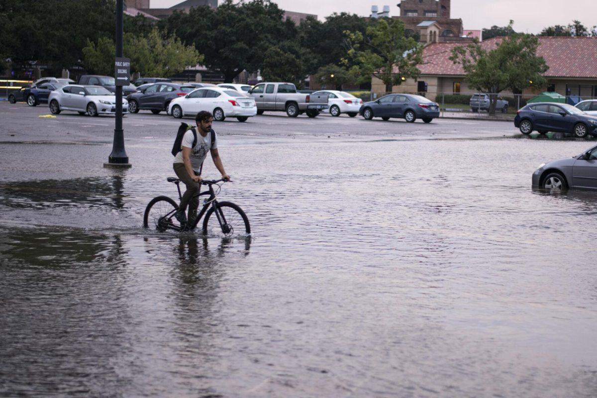 LSU graduate student Cory Calabria bikes through flooded waters Wednesday, Sept. 15, 2021, during Tropical Depression Nicholas in the Tiger Stadium parking lot on LSU's campus in Baton Rouge, La.