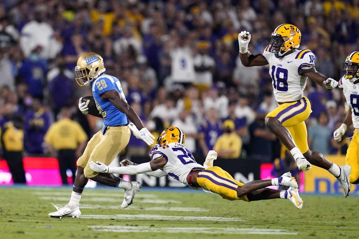 UCLA running back Brittain Brown (28) runs past LSU cornerback Cordale Flott, center, and linebacker Damone Clark (18) during the second half of an NCAA college football game Saturday, Sept. 4, 2021, in Pasadena, Calif. (AP Photo/Marcio Jose Sanchez)