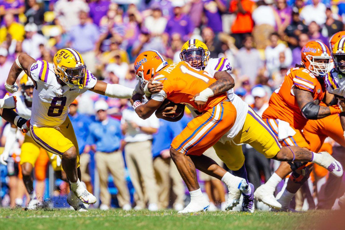 LSU football graduate student defensive tackle Neil Farrell Jr. (92) and sophomore defensive end BJ Ojulari bring down Florida redshirt-freshman quarterback Anthony Richardson (15) Saturday, Oct. 16, 2021, during LSU's 49-42 win against Florida at Tiger Stadium in Baton Rouge, La.