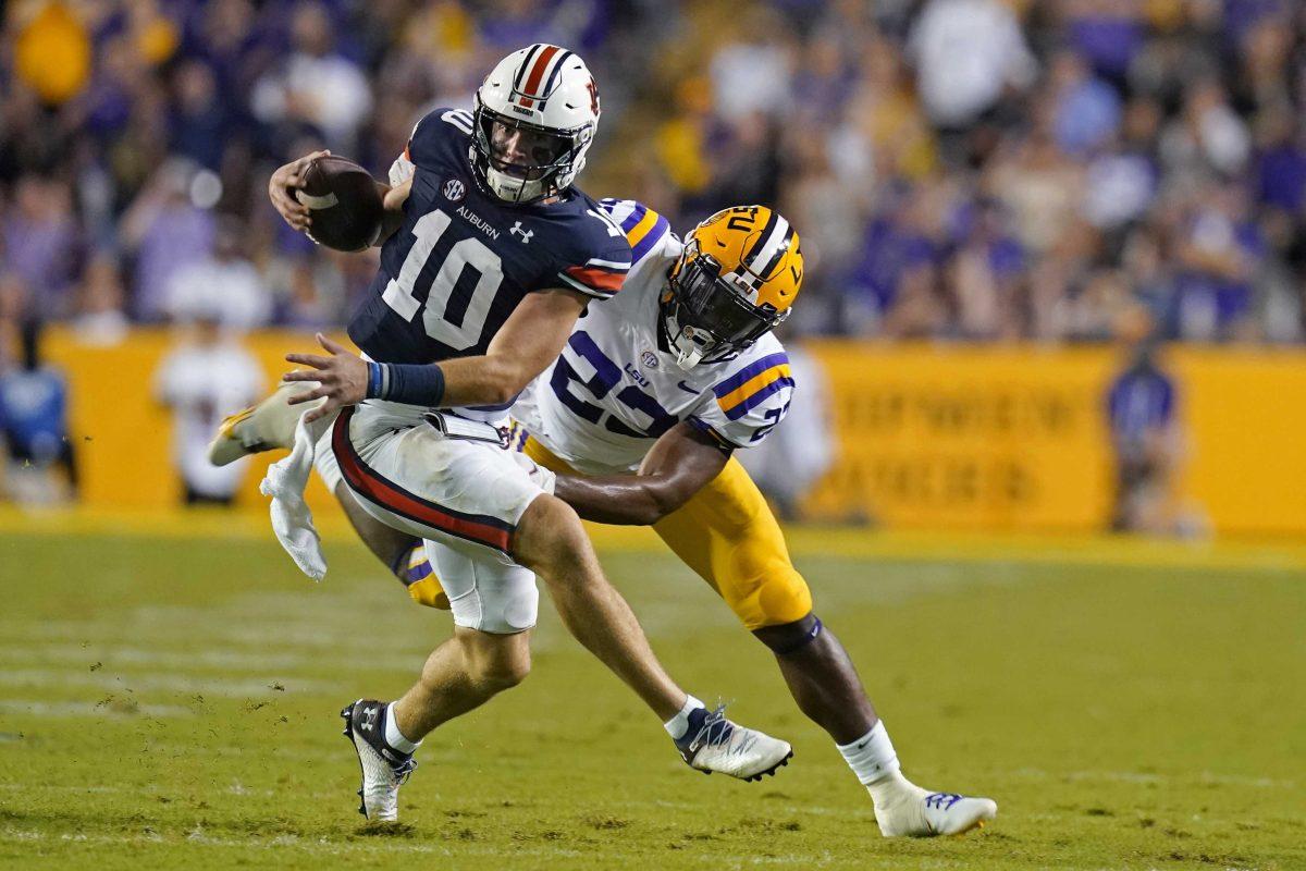 Auburn quarterback Bo Nix (10) scrambles to avoid LSU linebacker Micah Baskerville, on a play where he threw a touchdown pass, in the first half of an NCAA college football game in Baton Rouge, La., Saturday, Oct. 2, 2021. (AP Photo/Gerald Herbert)