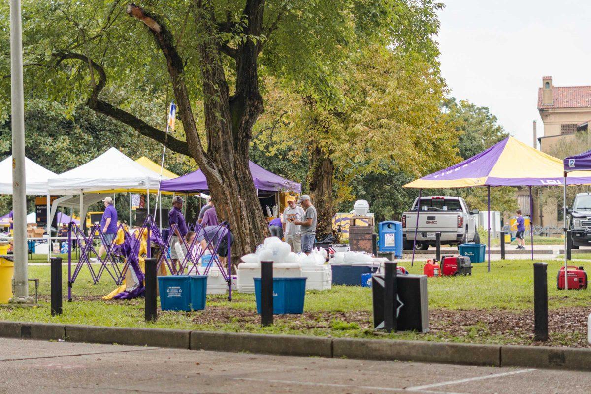 A group of men gather by a tree on Saturday, Oct. 2, 2021, while tailgating near Peabody Hall in Baton Rouge, La.