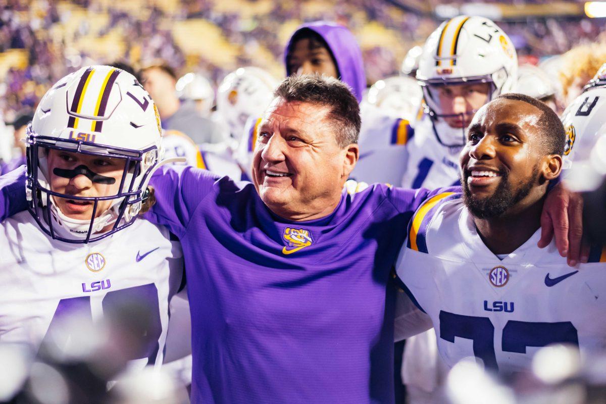 LSU football freshman linebacker Sloan Wright (48) and senior cornerback Lloyd Cole (32) put their arms around head coach Ed Orgeron for his final game Saturday, Nov. 27, 2021, during LSU's 27-24 win against Texas A&amp;M at Tiger Stadium in Baton Rouge, La.