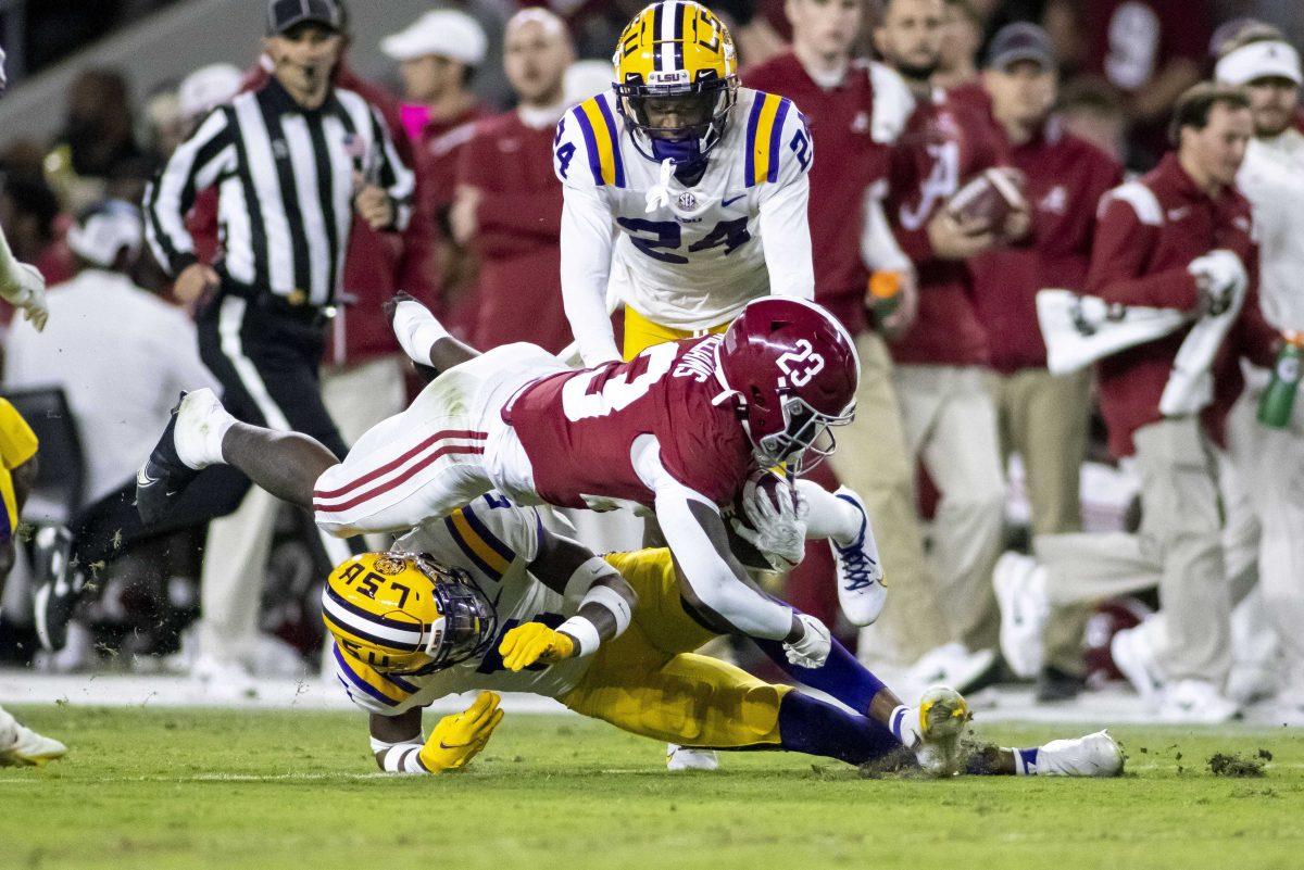 Alabama running back Roydell Williams (23) dives over LSU safety Jay Ward (5) during the first half of an NCAA college football game, Saturday, Nov. 6, 2021, in Tuscaloosa, Ala. LSU defensive back Darren Evans (24) looks on. (AP Photo/Vasha Hunt)