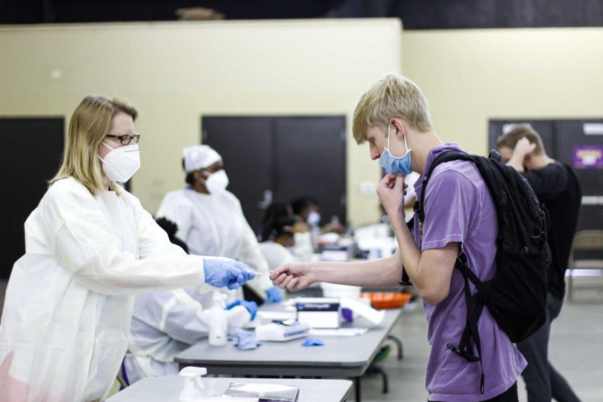 LSU COVID Testing assistant hands an LSU student the testing materials on Friday, September 10, 2021.