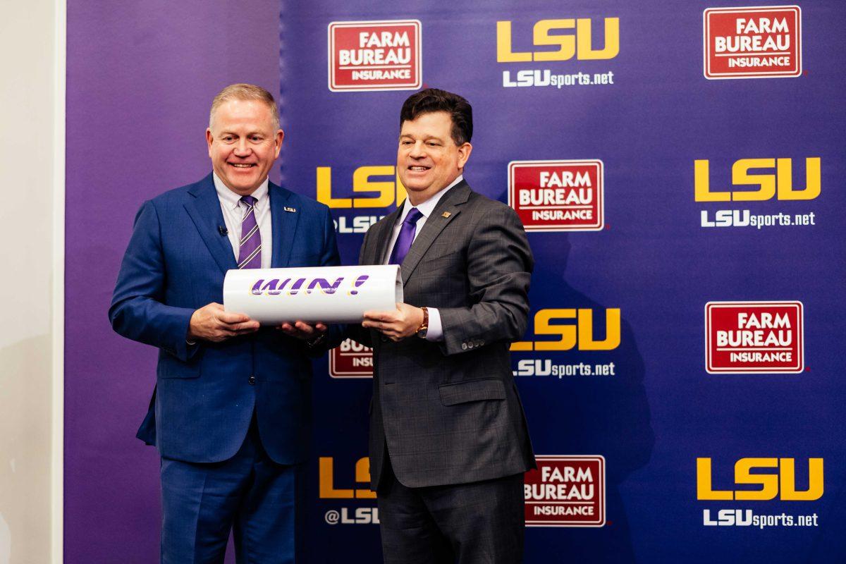 Brian Kelly poses along with athletics director Scott Woodward Wednesday, Dec. 1, 2021, while holding up LSU's "win!" bar during the press conference held in regard to his recent hire as LSU football's new head coach at the Bill Lawton Room in Tiger Stadium in Baton Rouge, La.