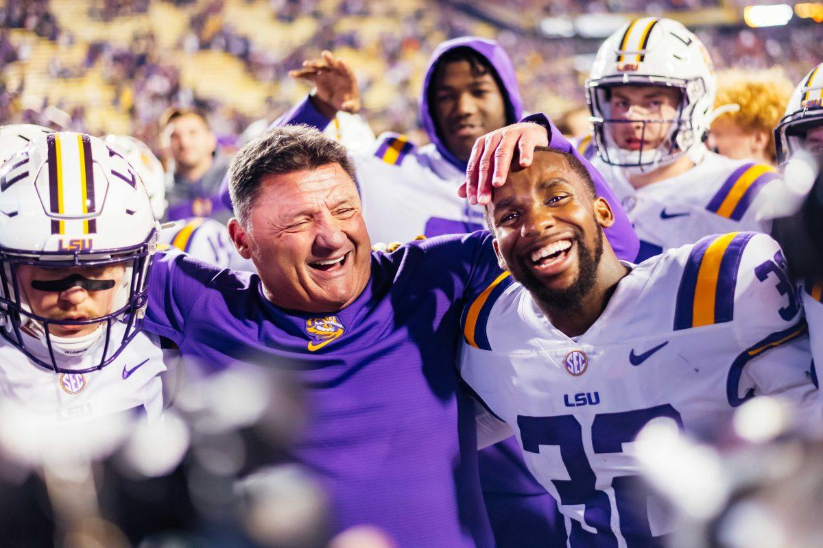 LSU football freshman linebacker Sloan Wright (48) and senior cornerback Lloyd Cole (32) put their arms around head coach Ed Orgeron for his final game Saturday, Nov. 27, 2021, during LSU's 27-24 win against Texas A&amp;M at Tiger Stadium in Baton Rouge, La.