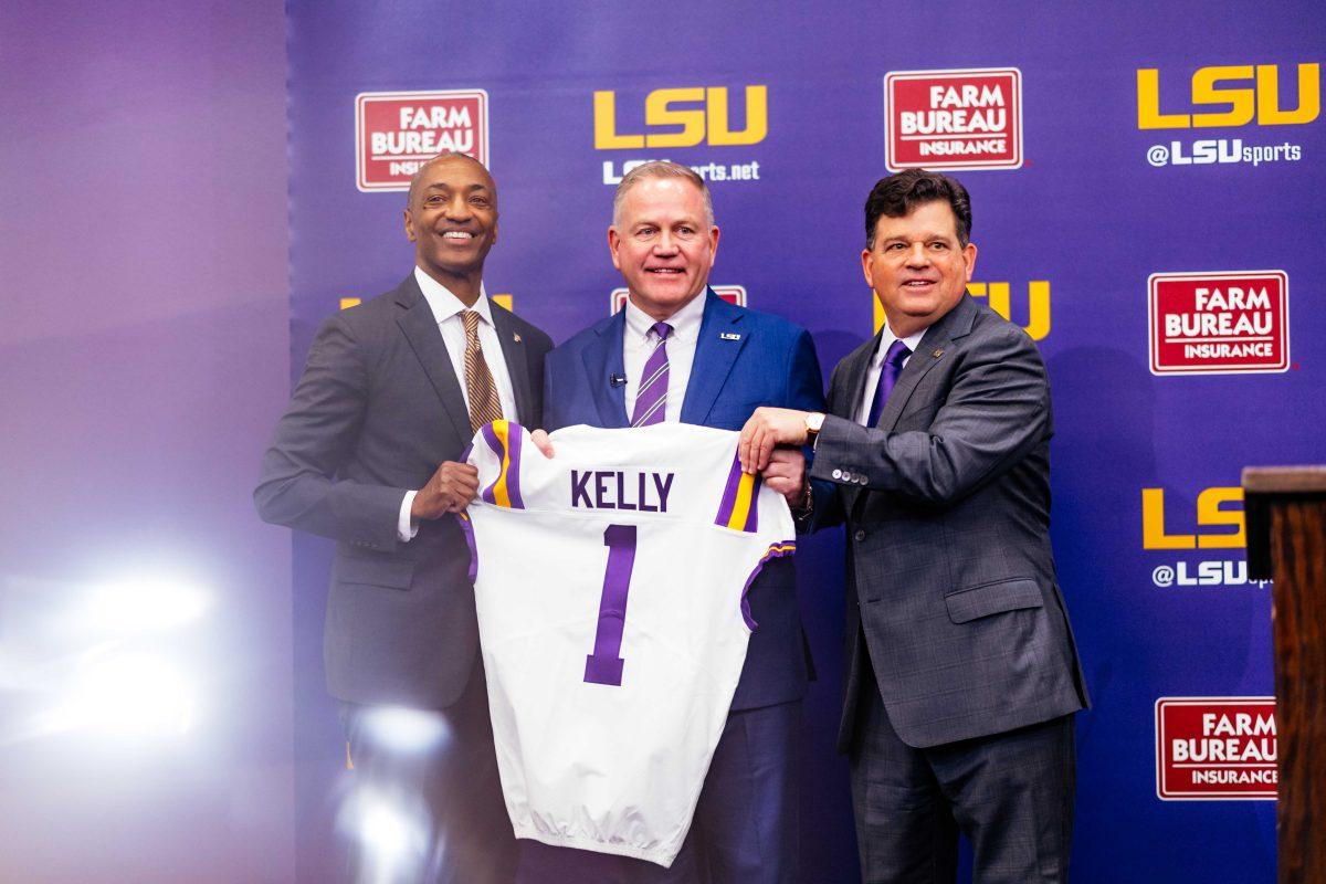 LSU football head coach Brian Kelly, athletics director Scott Woodward, and LSU President William F. Tate pose for a photo Wednesday, Dec. 1, 2021, while gifting a "Kelly" jersey during a press conference held in regard to Kelly's recent hire at the Bill Lawton Room in Tiger Stadium in Baton Rouge, La.