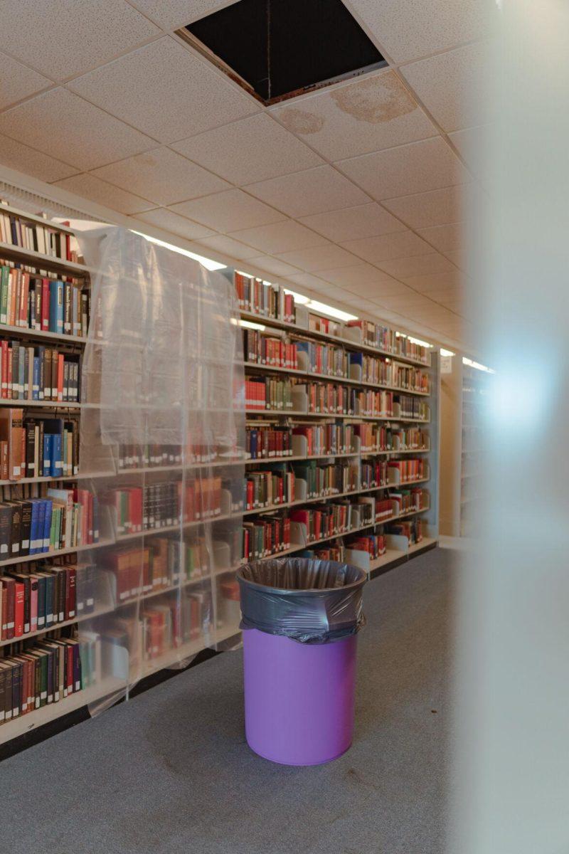 A tarp protects books from dripping water which collects in the garbage can on Tuesday, Jan. 18, 2022, in the LSU Library in Baton Rouge, La.