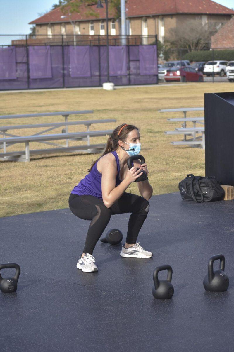 An LSU UREC instructor demonstrates squatting a kettlebell Wednesday, Jan. 26, 2022, at the UREC Outdoor Space.