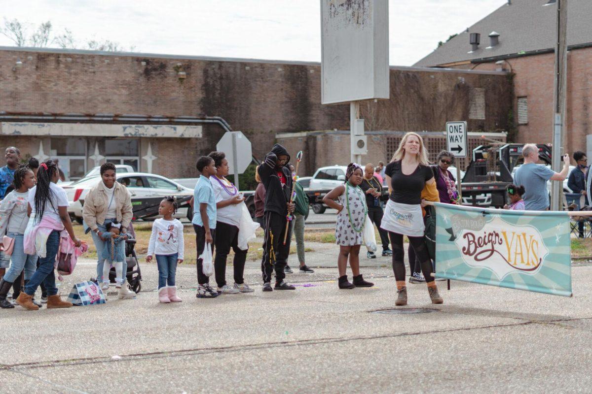 A line of people stands in the street on Sunday, Feb. 20, 2022, watching as the Mid City Gras parade goes by on North Boulevard in Baton Rouge, La.