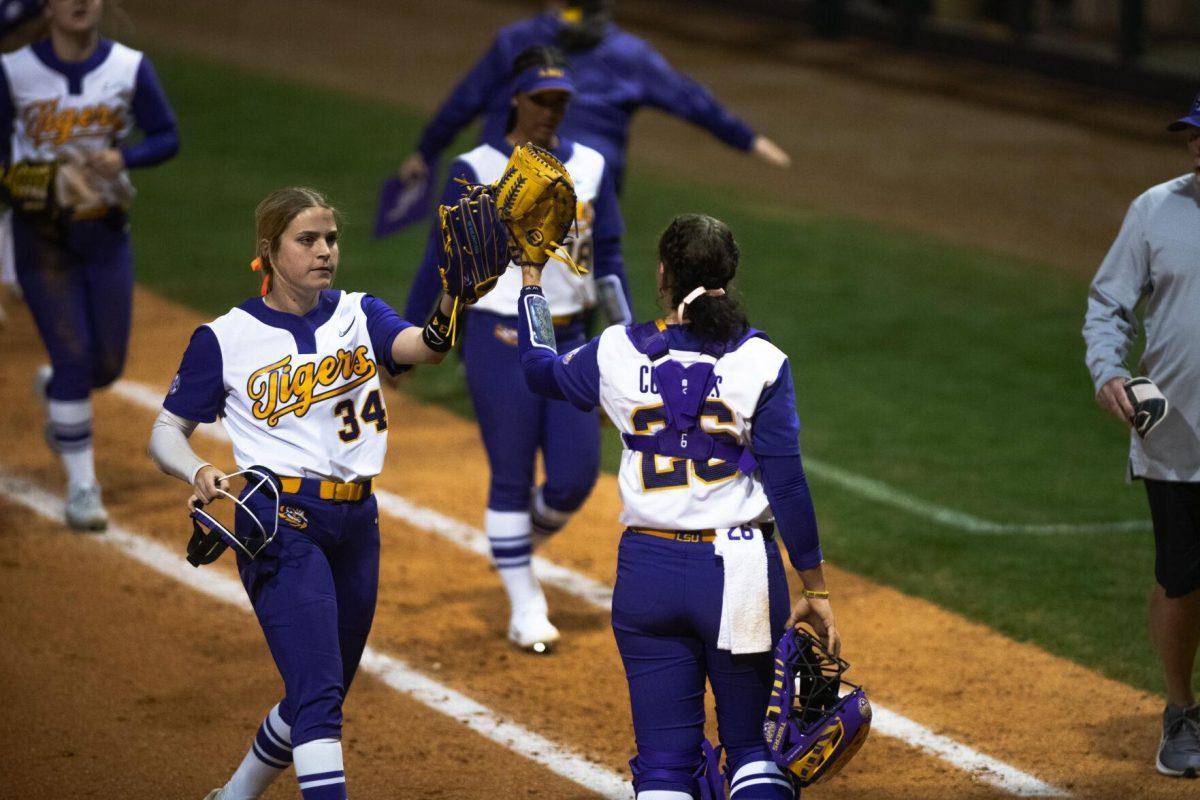 LSU softball freshman pitcher Raelin Chaffin (34) and junior catcher Morgan Cummins (26) tap gloves at the end of the inning Saturday, Feb. 12, 2022, during LSU’s 2-3 loss against Central Arkansas at Tiger Park on Skip Bertman Drive in Baton Rouge, La.