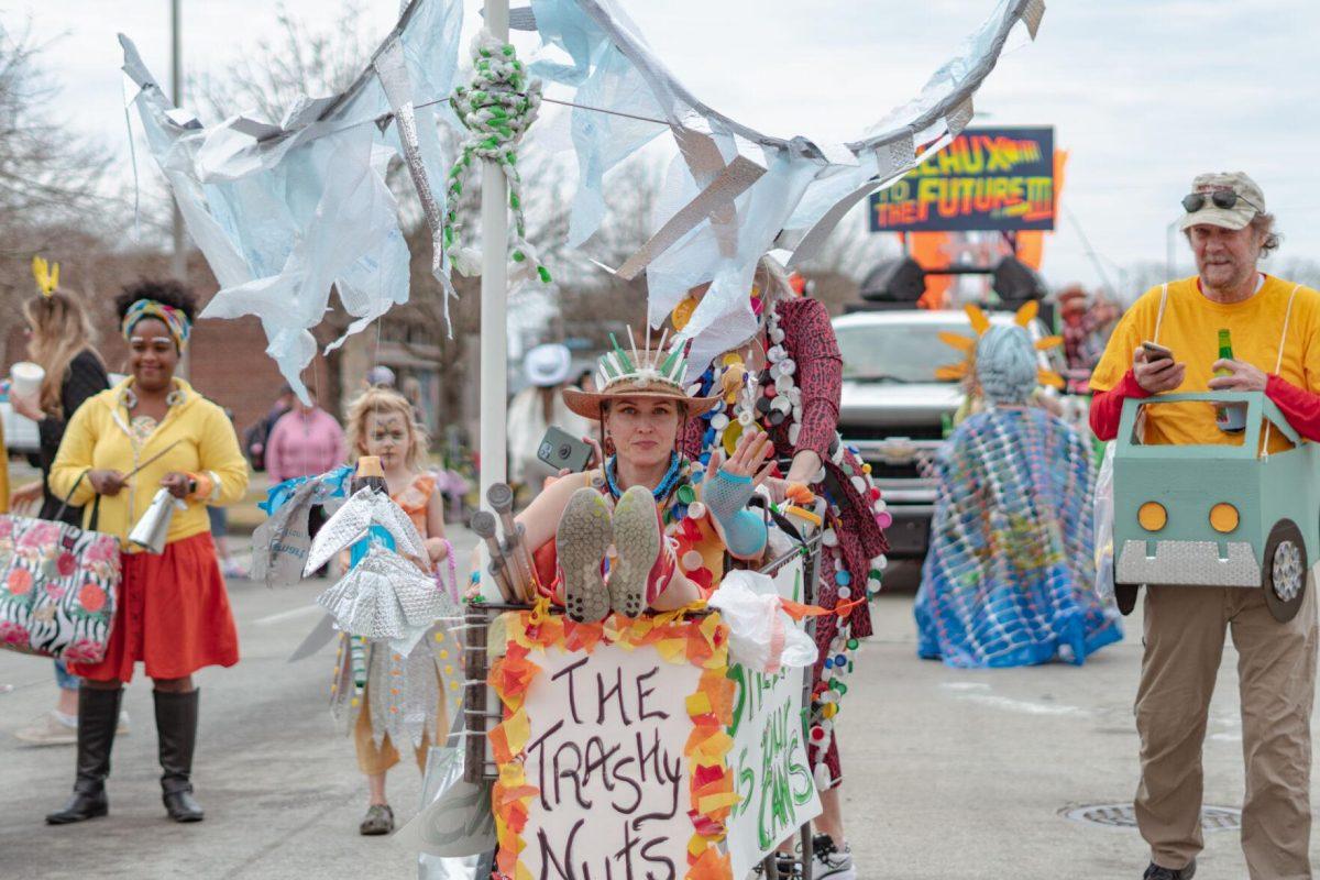 A woman in a shopping cart waves on Sunday, Feb. 20, 2022, as part of the Mid City Gras parade on North Boulevard in Baton Rouge, La.