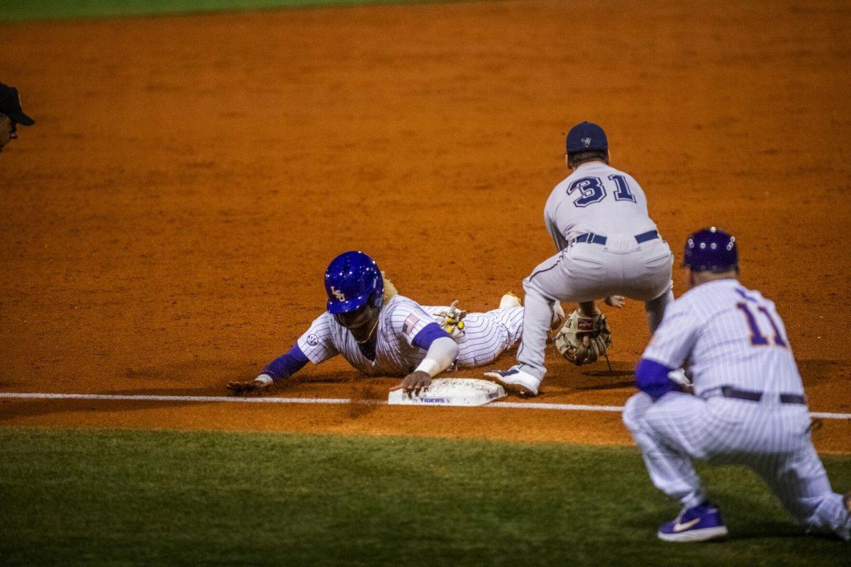 LSU baseball sophomore first baseman Tre Morgan III (18) slides third on an overthrow Friday, Feb. 18, 2022 before LSU's 13-1 win against Maine at Alex Box Stadium on Gourrier Avenue in Baton Rouge, La.