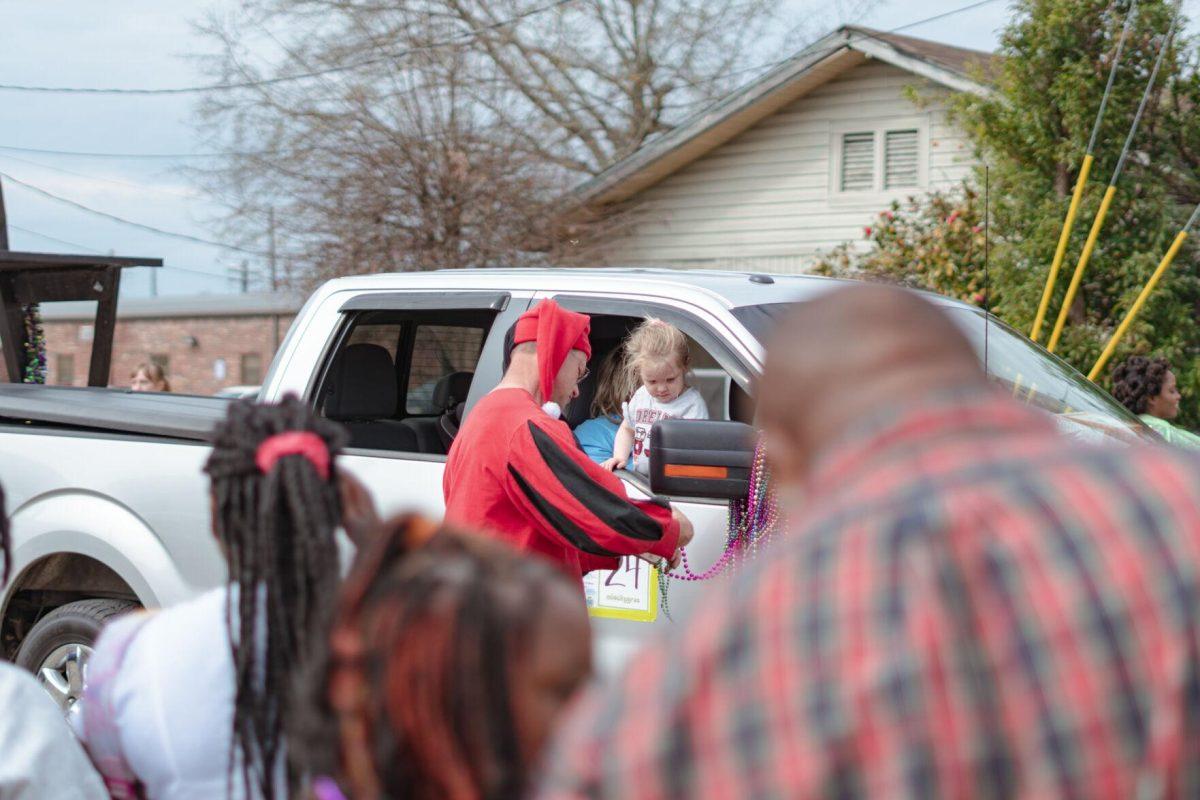 A man helps untangle beads for the young girl to throw on Sunday, Feb. 20, 2022, as part of the Mid City Gras parade on North Boulevard in Baton Rouge, La.