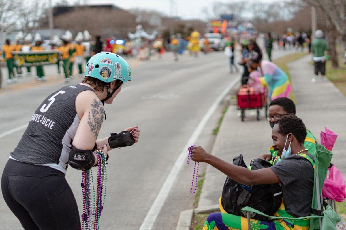 A woman in roller skates hands out beads on Sunday, Feb. 20, 2022, as part of the Mid City Gras parade on North Boulevard in Baton Rouge, La.