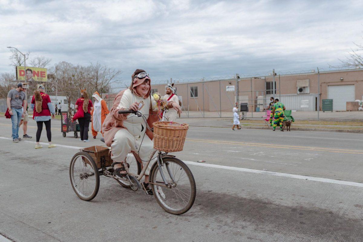 A woman rides a tricycle down the street on Sunday, Feb. 20, 2022, as part of the Mid City Gras parade on North Boulevard in Baton Rouge, La.