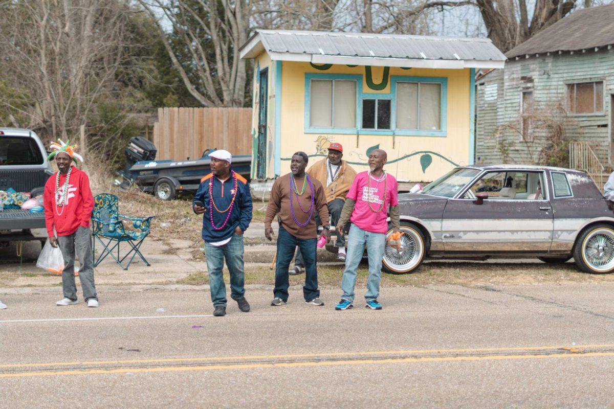 A group of men with beads around their necks watches the parade go by on Sunday, Feb. 20, 2022, at the Mid City Gras parade on North Boulevard in Baton Rouge, La.