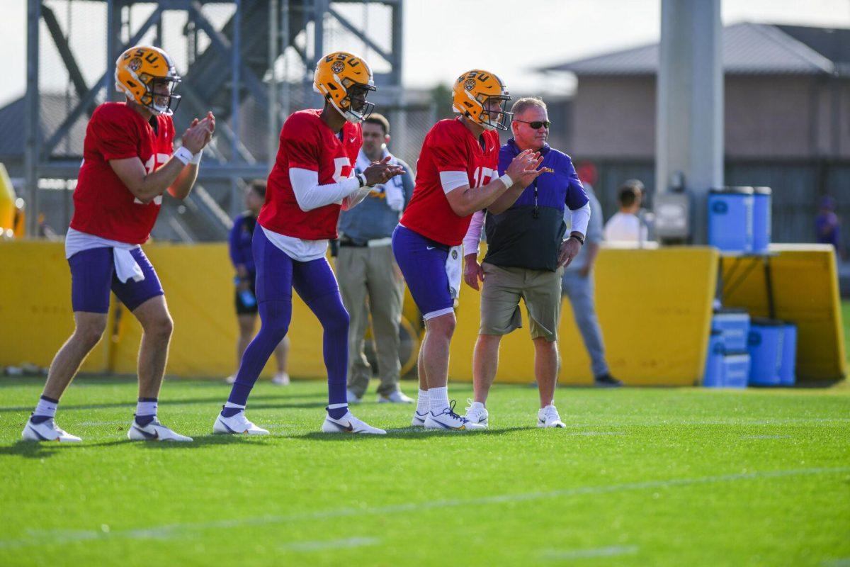 LSU football quarterbacks Myles Brennan (15), Jayden Daniels (5), and Garrett Nussmeier (13) wait for the ball while head coach Brian Kelly steps on Nussmeier's back foot Tuesday, March 29, 2022 during LSU's spring practice in Baton Rouge, La.