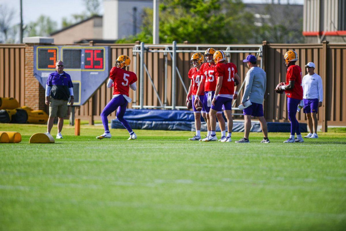 LSU football junior quarterback Jayden Daniels (5) throws the ball with head coach Brian Kelly viewing the drill Tuesday, March 29, 2022 during LSU's spring practice in Baton Rouge, La.