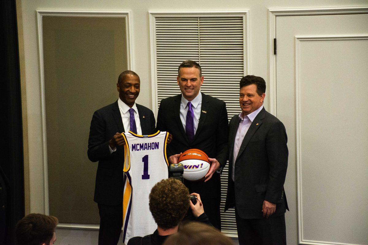 Matt McMahon poses along with athletics director Scott Woodward and president William F. Tate IV Wednesday, March 23, 2022, while holding up an LSU "win!" basketball and McMahon jersey during the press conference held in regard to his recent hire as LSU basketball's new head coach at the Bill Lawton Room in Tiger Stadium in Baton Rouge, La.