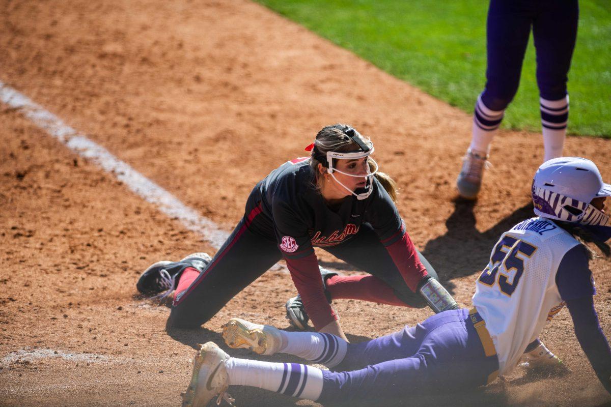 LSU softball redshirt sophomore Raeleen Gutierrez (55) and Alabama softball senior pitcher Montana Fouts (14) look at the umpire to see if Raeleen is safe or out Saturday, March 12, 2022 during LSU's 13-6 win against Alabama at Tiger Park in Baton Rouge, La.