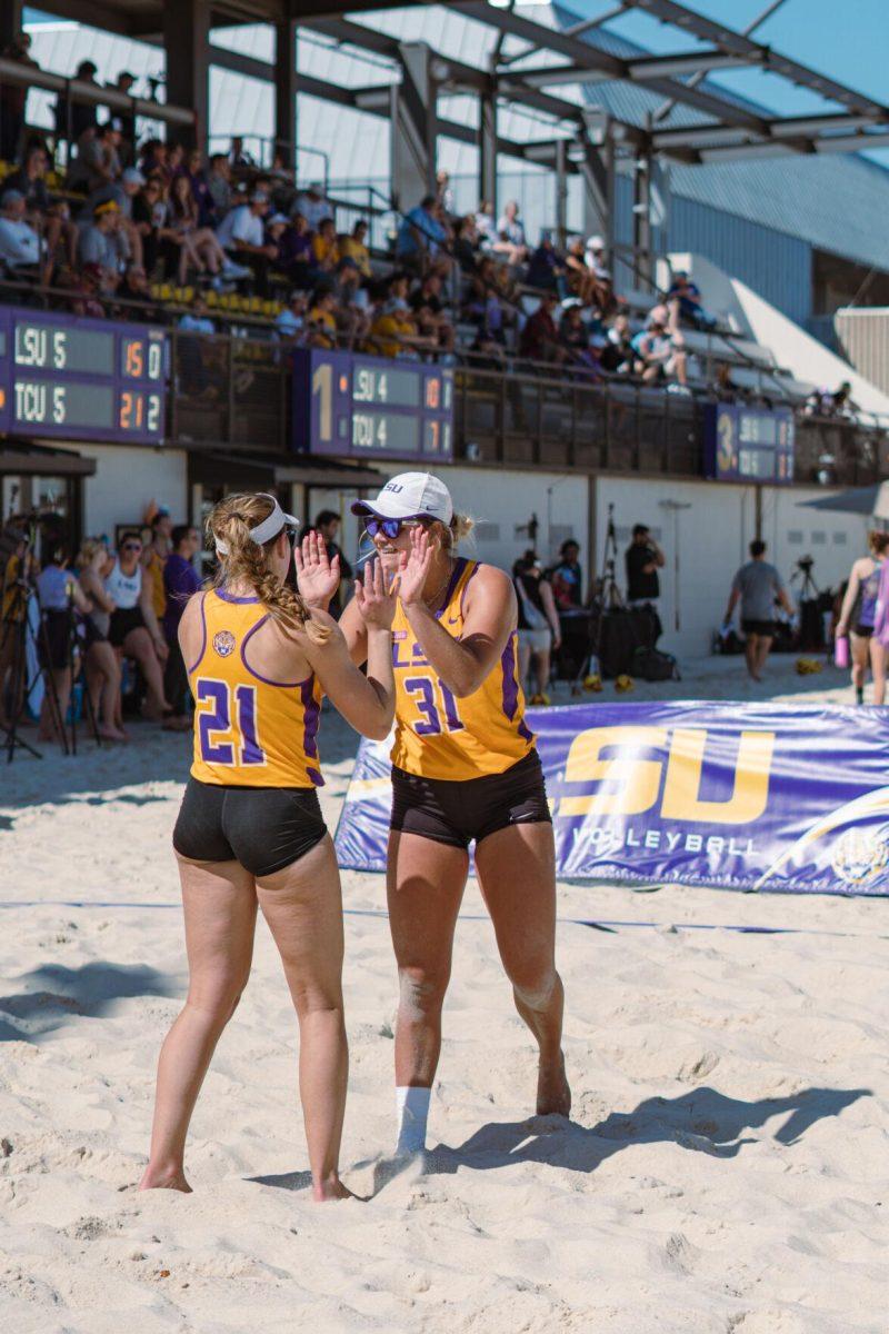 LSU beach volleyball freshman Cassidy Chambers (21) and redshirt freshman Brooke Blutreich (31) high five on Sunday, March 27, 2022, during LSU&#8217;s 1-4 loss against TCU at the Beach Volleyball Stadium on Cypress Drive in Baton Rouge, La.