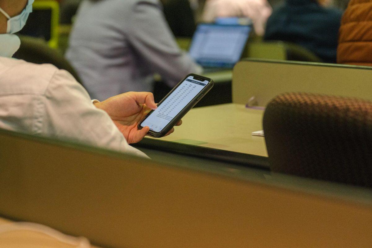 One Faculty Senator references the meeting agenda on a cellphone on Thursday, March 24, 2022, inside the LSU Law Center on Highland Road in Baton Rouge, La.