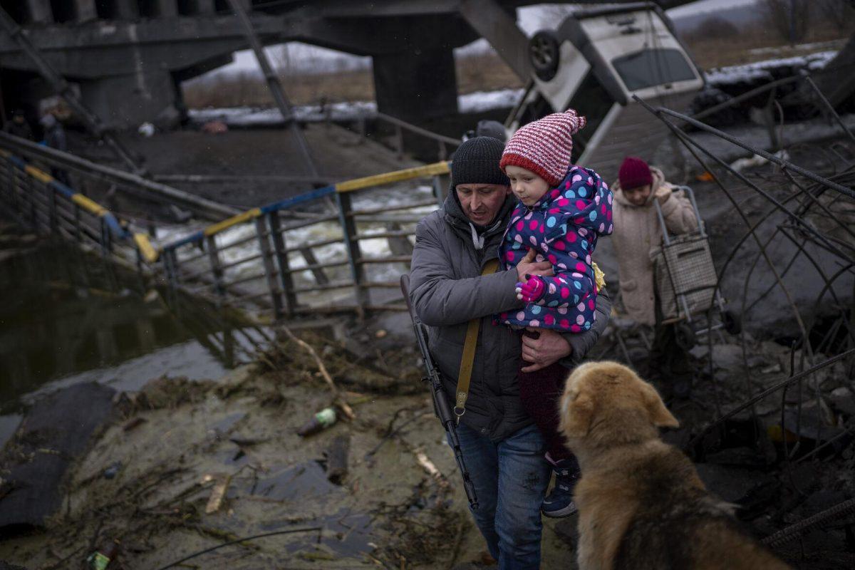 Local militiaman Valery, 37, carries a child as he helps a fleeing family across a destroyed bridge, on the outskirts of Kyiv, Ukraine, Wednesday, March 2. 2022. Russia renewed its assault on Ukraine&#8217;s second-largest city in a pounding that lit up the skyline with balls of fire over populated areas. That came Wednesday even as both sides said they were ready to resume talks aimed at stopping the new devastating war in Europe. (AP Photo/Emilio Morenatti)