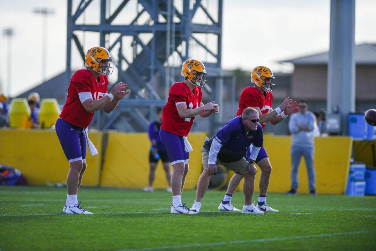 LSU football quarterbacks Garrett Nussmeier (13), Walker Howard (14), and Myles Brennan (15) prepare for the ball while head coach Brian Kelly stands in between them Tuesday, March 29, 2022 during LSU's spring practice in Baton Rouge, La.