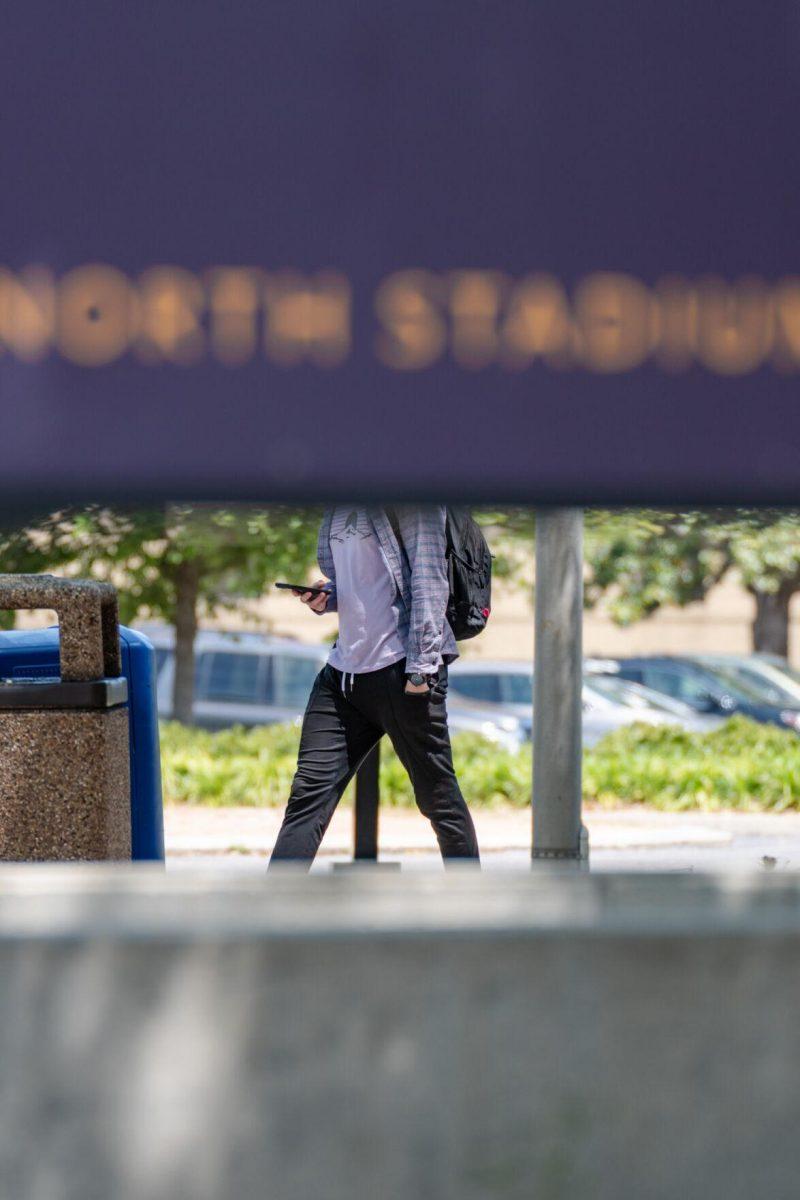 The Journalism building sign creates the appearance of being headless for a student passing by on Tuesday, April 19, 2022, on North Stadium Drive in Baton Rouge, La.