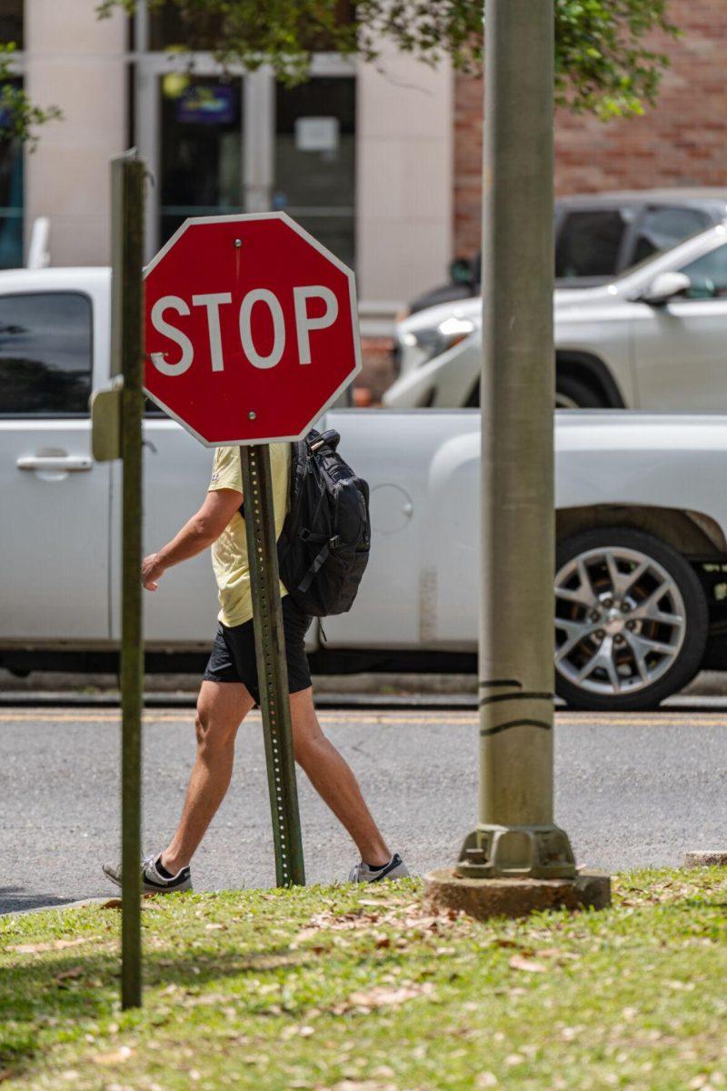 A stop sign causes the walker to appear headless on Thursday, April 21, 2022, near Acadian Hall on Highland Road in Baton Rouge, La.